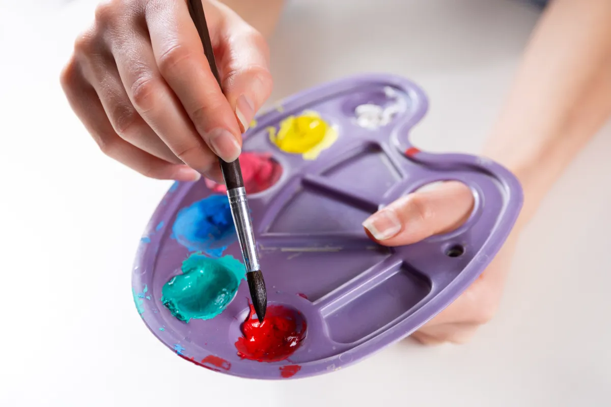 female artist mixing paints in small palette